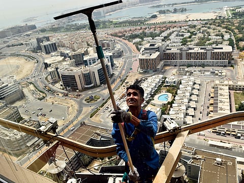 A worker cleaning the window at the 40th floor of high rise building in Dubai Marina