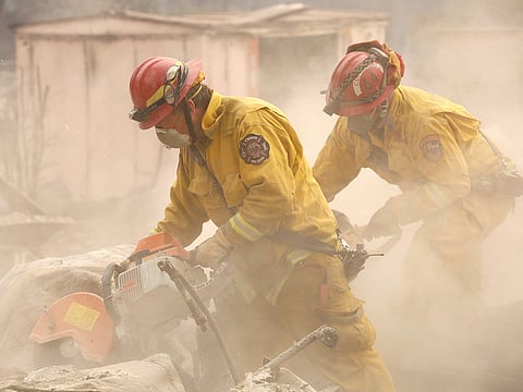 Cal Fire firefighters comb through a house destroyed by the Camp Fire in Paradise, California, U.S., November 13, 2018.
