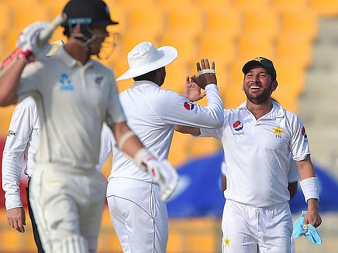 Pakistani spinner Yasir Shah (R) celebrates with teammate after taking the wicket of New Zealand batsman Ajaz Patel during the first Test match between Pakistan and New Zealand at the Sheikh Zayed International Cricket Stadium in Abu Dhabi on November 16, 2018. 