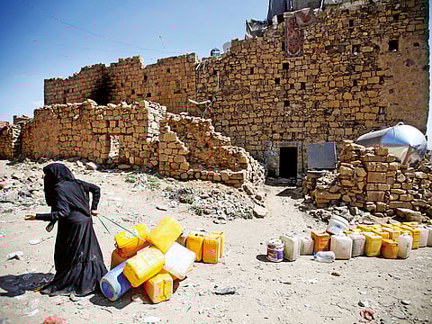 A woman displaced from the Red Sea port city of Hodeidah pulls empty canisters outside her family shelter in Sanaa, Yemen.