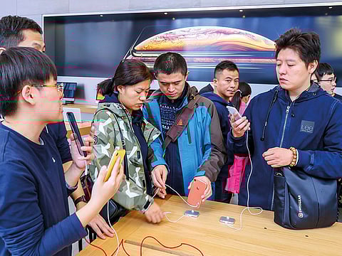 Customers listen as a staff member (L) introduces the iPhone XR at an Apple store in Shanghai.