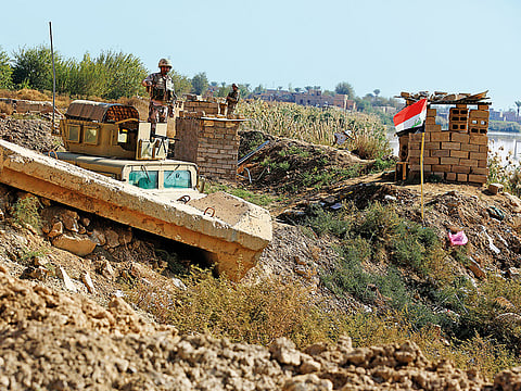 Iraqi soldiers stand on the Iraqi side of the border with Syria, in the town of Qaim, Anbar province, Iraq. Life in Qaim has been put on hold as just across the border in Syria, fighting rages against one of the last major enclaves of the Islamic State group.