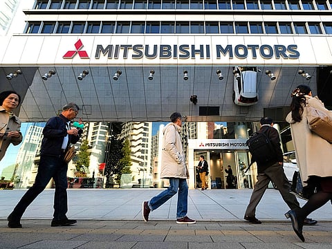 People walk past the headquarters of Mitsubishi Motors in Tokyo.