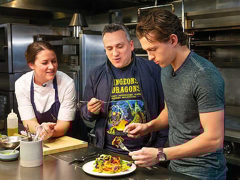 Chef Jessica Largey looks on as director Joe Russo and actor Tom Holland taste a dish she just cooked at the Cooking with “The Avengers” event at the Simone Restaurant in Los Angeles.