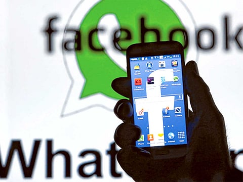 A man holding a smart phone with a Facebook logo as its screen wallpaper [Illustrative image] 