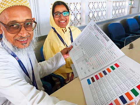 Scorer Hakim Jariwala with his wife Nafisa and the special T10 scorebook he created for the T10 League.