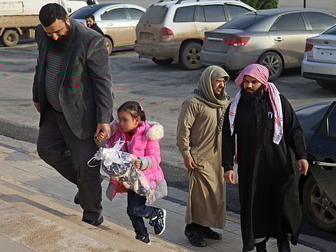 Members of the civilian branch of the powerful Hayat Tahrir Al Sham (HTS) alliance, which is led by the jihadists of Syria's former Al Qaeda affiliate, escort four-year-old girl named Yasmine near the Bab al-Hawa crossing with Turkey. 
