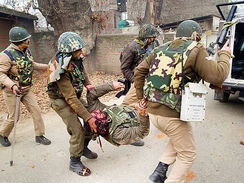 Paramilitary soldiers carry their colleague wounded during clash with protesters near the site of a gunfight in Badgam district, Kashmir, yesterday.