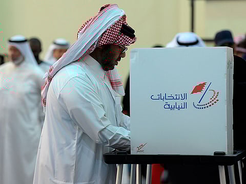A Bahraini voter casts his ballot at a polling station in the Bahraini city of Al-Muharraq, north of Manama on November 24, 2018, as they wait to cast their vote in the parliamentary election. 