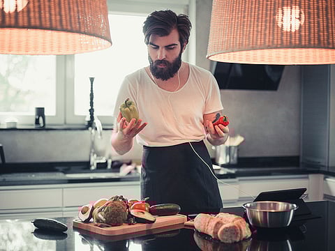 Bearded man cooking and listening to music in the kitchen