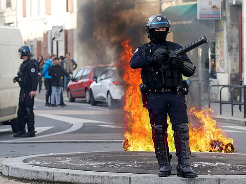 A French riot policeman stands next to a burning trash container as youth and students protest against reform plan in the streets of Bordeaux, France, December 5, 2018.