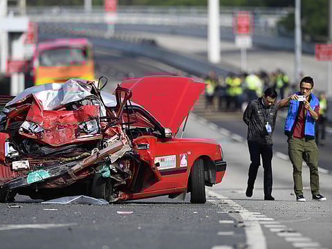 Police take photos of a crushed taxi after a coach (back) collided with it in Hong Kong on November 30, 2018.