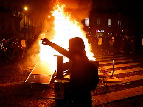 Demonstrators gather around a burning barricade during clashes with riots police, in Paris, France
