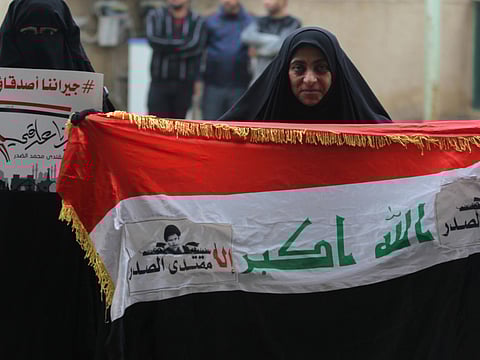Iraqi Muslim Shiite women hold their national flag and a sign in Arabic reading: "Our neighbours are our friends but not our masters. Our decision is an Iraqi decision", after prayers in Baghdad's Sadr City district on December 6, 2018. Shiite cleric Moqtada Sadr ordered followers in prayer today in the mosques of Iraq in order to "speed up the formation of the Iraqi government away from the intervention of neighbouring countries in the formation of the government headed by Adel Abdul Mahdi". / AFP / AHMAD AL-RUBAYE