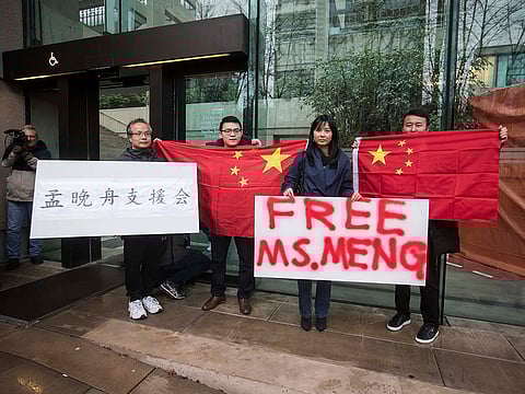 Supporters hold signs and Chinese flags outside British Columbia Supreme Court during the third day of a bail hearing for Meng Wanzhou, the chief financial officer of Huawei Technologies, in Vancouver, on Tuesday December 11, 2018. 