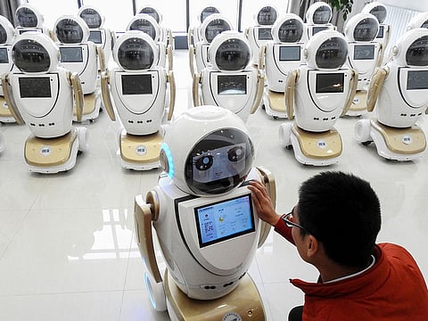 An employee checks robots used for customer services at a factory in Lianyungang in China's eastern Jiangsu province.