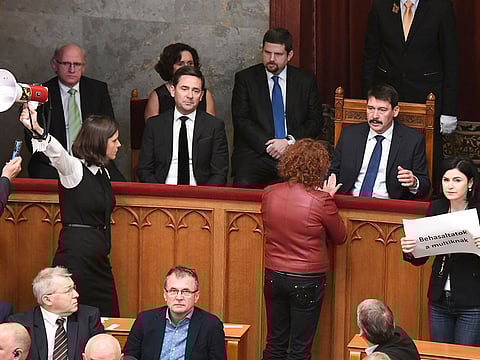 Hungarian President Janos Ader (2R) listens to the opposition politicians, Agnes Vadai (front, C) of the Democratic Coalition next to independent representative Bernadett Szel (L) holding a siren-horn and Agnes Kohalmi of the Hungarian Socialist Party in the hall of the parliament building in Budapest on December 12, 2018. Rare scenes of chaos gripped the Hungarian parliament as it passed changes to the labour code proposed by Orban's party that critics have dubbed a "slave law". 