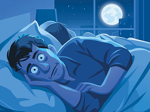 A young man lying in his bed, trying to sleep. 