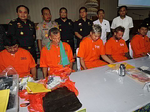(L to R) Jorge Rafael Albornoz Gammara of Peru, Frank Zeidler of Germany, Cui Bao Lin of China, an unidentified man, and Hamdi Izham Hakimi of Malaysia, all suspected of smuggling or possessing drugs in the country, sit at a table as they are displayed by authorities to the media at a press conference at the customs office near Ngurah Rai international airport in Denpasar on the resort island of Bali on December 13, 2018.