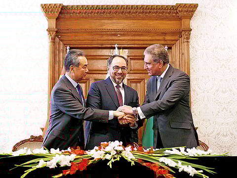 China’s Foreign Minister Wang Yi, Afghanistan’s Foreign Minister Salahuddin Rabbani and Pakistan’s Foreign Minister Shah Mahmoud Quraishi shake hands after a memorandum of understanding on cooperation in fighting terrorism signed in Kabul