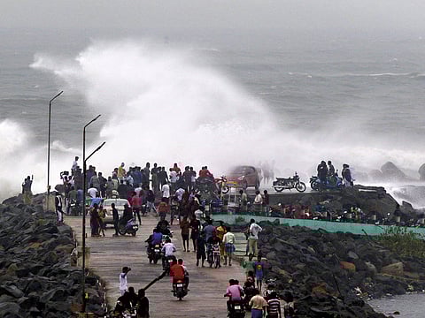 People walk along the breakwater at Kasimedu fishing harbour in Chennai. Both Andra Pradesh and Tamil Nadu are bracing for cyclone Phethai, which is expected to hit today.