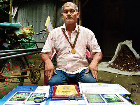 Ohid Sarder, 53, poses with medals, crests, and certificates received for his tree-saving work in Jessore, a western district of Bangladesh.