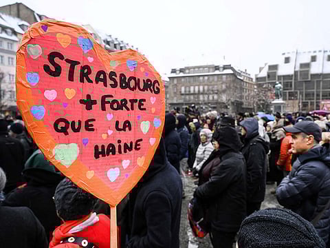 A woman holds a sign reading "Strasbourg stronger than hate"  as she attends a gathering around a makeshift memorial at Place Kleber, in Strasbourg, on December 16, 2018 to pay a tribute to the victims of Strasbourg's attack.