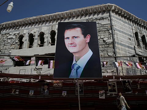 A man walks past a banner depicting Syrian president Bashar al-Assad in Douma, outside Damascus, Syria.