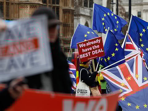 Pro and anti Brexit demonstrators wave their placards and flags outside the Houses of Parliament in London.
