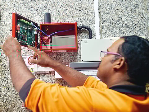 A technician installs a smart fire alarm system in a residential building.