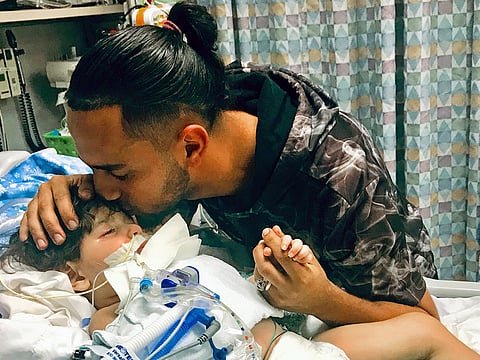 Ali Hassan kissing his dying 2-year-old son Abdullah.