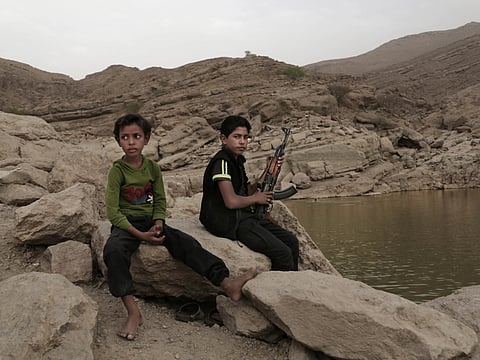 In this July 30, 2018, photo, a 17 year-old boy holds his weapon in High dam in Marib, Yemen. Al Houthis have widely deployed child soldiers in the conflict. 