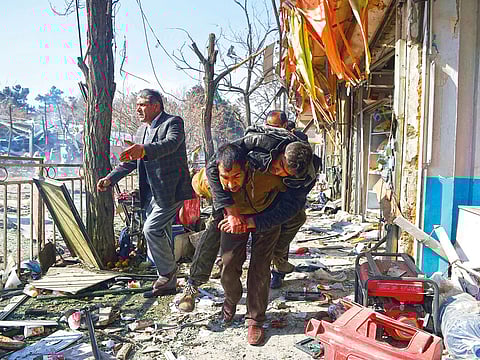 Afghan volunteers carry a body at the scene of a car bomb exploded in front of the old Ministry of Interior building in Kabul on January 27, 2018.