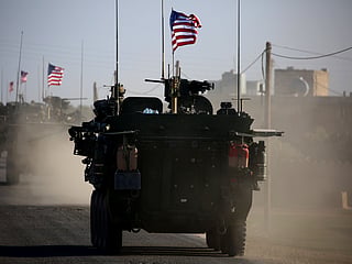 US military vehicles carrying American flags patrol in Syria, where Washington has maintained troops as part of its regional military presence.  