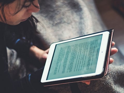 A woman reading a book on her iPad.