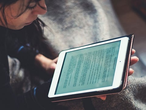 A woman reading a book on her iPad.