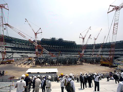 In this July 18, 2018, file photo, journalists visit New National Stadium under construction during a media tour to the venues of the Tokyo 2020 Olympics in Tokyo. 