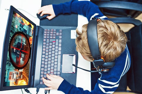 A boy sits in front of a computer.