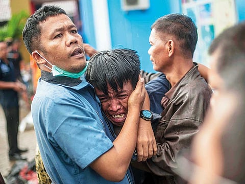A man grieves after identifying his relative among the bodies of tsunami victims in Carita