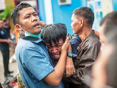 A man grieves after identifying his relative among the bodies of tsunami victims in Carita