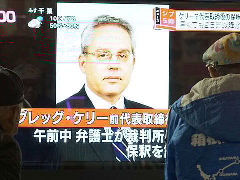 Pedestrians looking at a television news program featuring former former Nissan representative director Greg Kelly in Tokyo