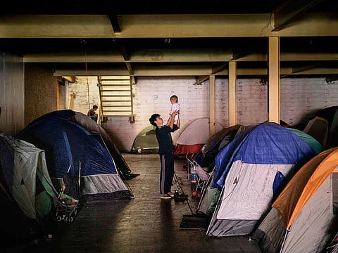 A man from Honduras holds a baby inside an empty warehouse used as a shelter set up for migrants in downtown Tijuana, Mexico, Tuesday, Dec. 25, 2018.