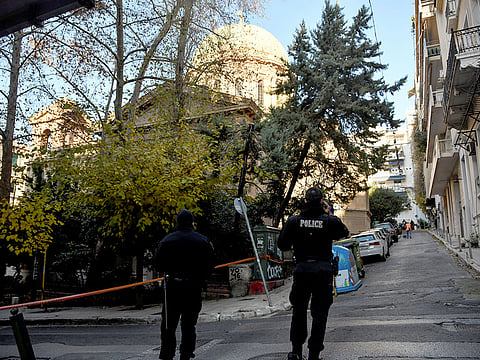 Police officers stand guard outside the Saint Dionysios church, following the detonation of an explosive device in Athens, Greece.