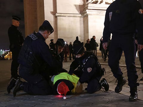 A Yellow vests (Gilets jaunes) anti-government protester, wearing a Father Christmas hat, is arrested by French police at the Arc de Triumph in central Paris on December 24, 2018.