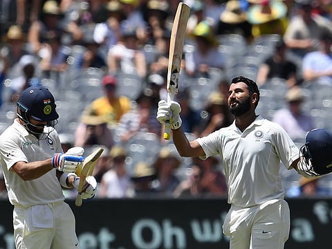 India's batsman Cheteshwar Pujara (R) celebrates reaching his century (100 runs) with team's captain Virat Kohli during day two of the third cricket Test match between Australia and India in Melbourne on December 27, 2018.