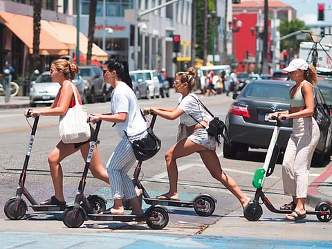 Women ride shared electric scooters in Santa Monica.