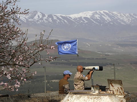 UN members look through binoculars as they monitor the Israel-Syria border in the Israeli-annexed Golan Heights.