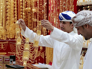 An employee shows a customer gold jewellery in a shop at the Gold Souq in Dubai