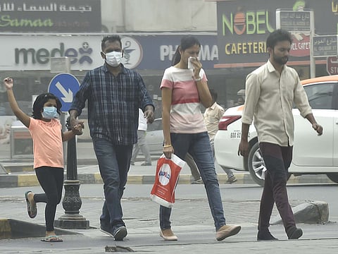 People cover their faces with masks during the sandstorm in Sharjah