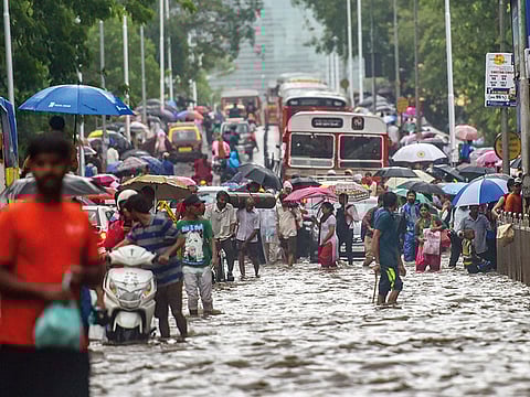Vehicles and pedestrians wade through a flooded street following heavy monsoon showers in Mumbai.
